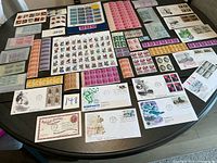 Wide view of table with numerous unused U.S. stamp blocks, sheets and first day covers