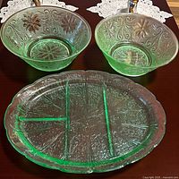 Two green depression glass bowls and divided platter on table showing full pattern and color.