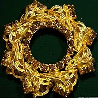 Front view showing gold-tone filigree wreath and brown rhinestones