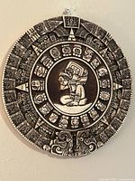 Front view of Aztec calendar plaque showing entire design and hanging loop