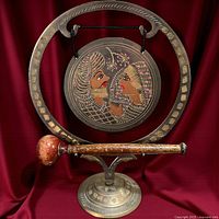 Front view of brass gong, stand and striker mallet