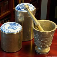 Brass mortar with pestle, two brass canisters; lids visible