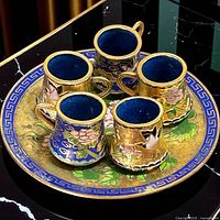 Top view of tray with five cups showing enamel designs