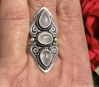 Ring worn on finger showing elongated design and three moonstones
