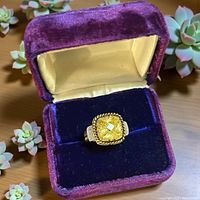 Ring in purple velvet box, clear view of yellow stone and silver halo