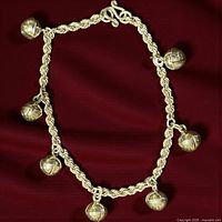 Full view of sterling silver bell charm bracelet laid flat on red fabric