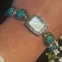 Watch worn on wrist showing dial and turquoise cabochon links