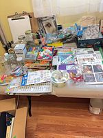 Full table view of assorted craft supplies, books, jars and clipboards