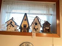 All four painted wooden birdhouses on window ledge