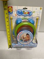 Front view of sealed package showing water drums, drumsticks, branding, age rating