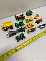 Group shot of all 12 miniature vehicles lined up beside tape measure