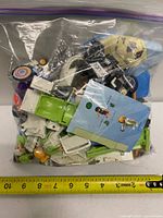 Full zipper bag filled with mixed Playmobil parts shown beside tape measure