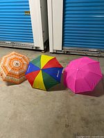 All three umbrellas opened: orange floral, multicolor panel, pink