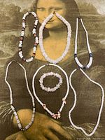 All six jewellery pieces laid out on surface: five necklaces and one bracelet