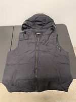 Front view of black quilted puffer vest with hood
