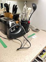 Countertop view of toaster, hand mixer, knife block, utensil caddy and ladle