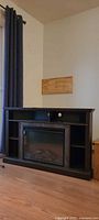 Front view of dark brown corner TV stand with electric fireplace and storage cubbies