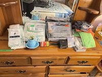 Full lot view on dresser showing all packaged linens, socks, cloths and small items