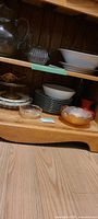 Shelf view showing amber ruffled bowl beside white patterned bowls and plates