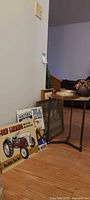 Side table, framed print, tin signs grouped against wall