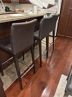 Two of the three brown faux-leather bar stools at counter