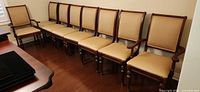 Eight matching dining chairs lined against wall