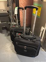 Two identical black Delsey wheeled carry-on bags with handles extended