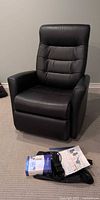 Front view of black leather power glider recliner chair with accessories on floor