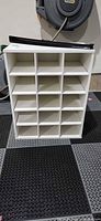Front view of white composite cubby shoe rack with 15 compartments