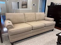 Front view of beige Barrymore sofa showing three seat and back cushions, rolled arms, wooden legs