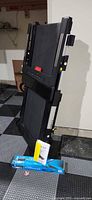Treadmill folded upright with accessory kit and manual at base