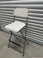 Front angled view of folded-open white IKEA Franklin stool