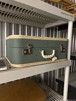 Full view of green suitcase closed on shelf