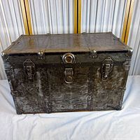Front of metal-clad antique trunk showing riveted panels, lock and clasps