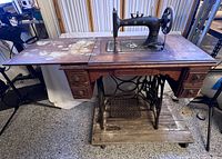 Full view of New Home treadle sewing machine in oak cabinet, treadle base visible