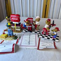Group shot of four Coca-Cola bear figurines with certificates