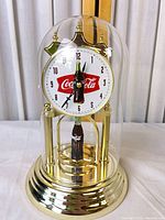 Front view of Coca-Cola rotating anniversary clock under glass dome