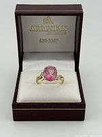 Ring in presentation box showing pink stone and gold band