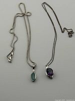 Two sterling silver necklaces with pendants displayed beside coin for scale