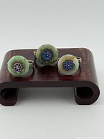 Front view of three jade and enamel gilt silver rings on stand