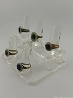 Front and side view of all five rings on acrylic stand