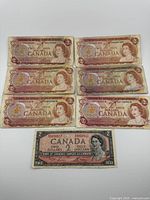Fronts of six red 1974 series and one black-grey 1954 series $2 bills