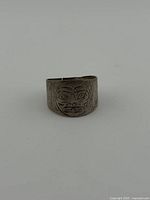 Front view showing engraved Indigenous face motif