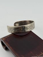 Front angled view of sterling silver cuff showing engraved motif and form