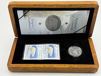 Open hardwood box showing coin, stamps and certificate