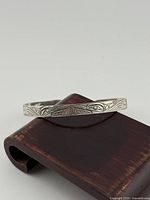 Front view of sterling bangle displaying main engraved motif