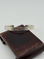 Full view of sterling silver Coast Salish cuff resting on stand
