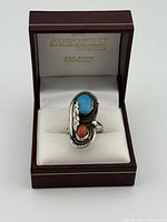 Front view of ring in box showing turquoise and coral stones
