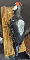 left side view of carved woodpecker on plank showing paint and wear