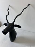 Front angled view of black metal antelope head with long spiral horns